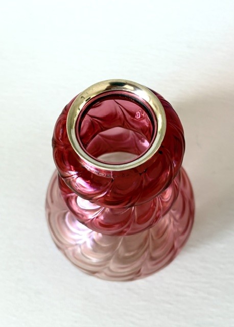 An Art Nouveau iridescent glass vase featuring a lobed, swirling magenta to pink body fitted with a polished sterling silver rim collar. View IV