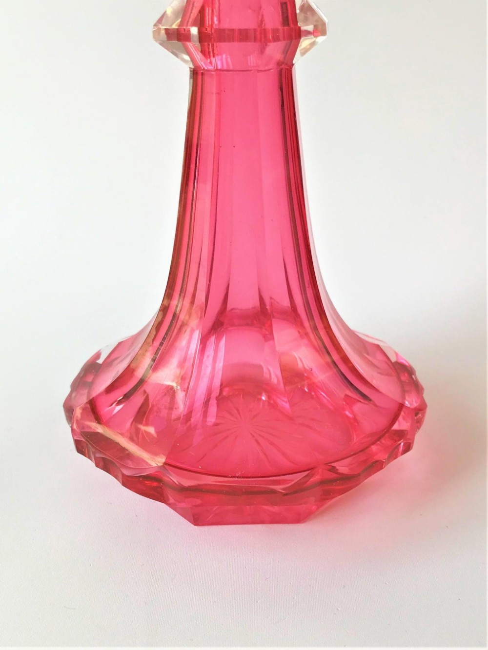A tall Victorian cranberry and clear cut glass cologne bottle featuring an elongated pointed spire stopper, faceted neck, and flared base. View IV