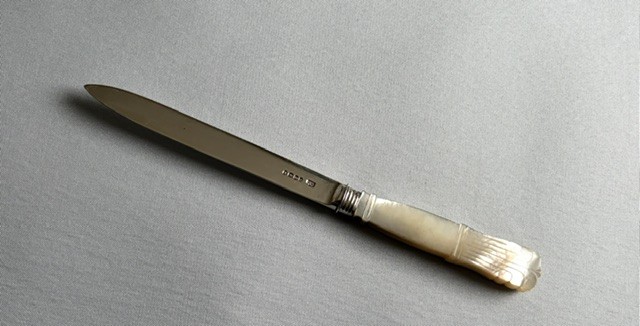 An antique Georgian letter opener featuring a tapered silver blade with stamped hallmarks and a carved cream mother of pearl handle. View VI