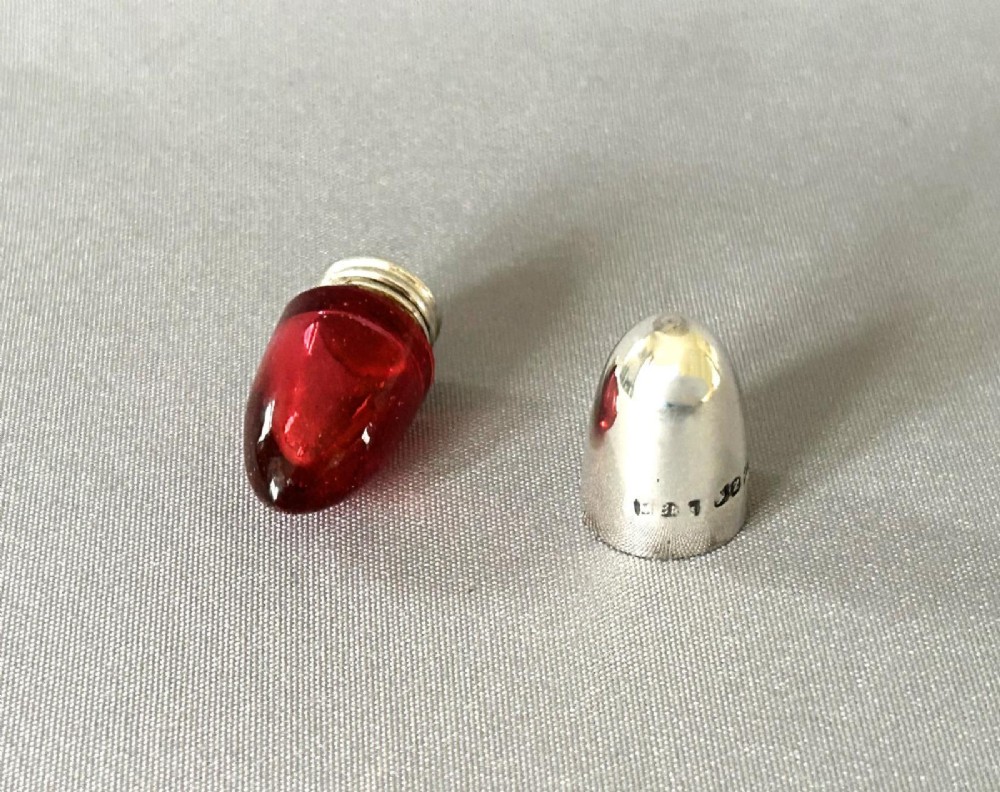 A small bullet-shaped antique scent bottle featuring a polished silver cap and a red cranberry glass body. View III