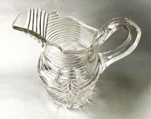 A clear cut-glass water jug featuring a loop handle, horizontal step cuts around the neck, and diamond facets across the lower body. View III