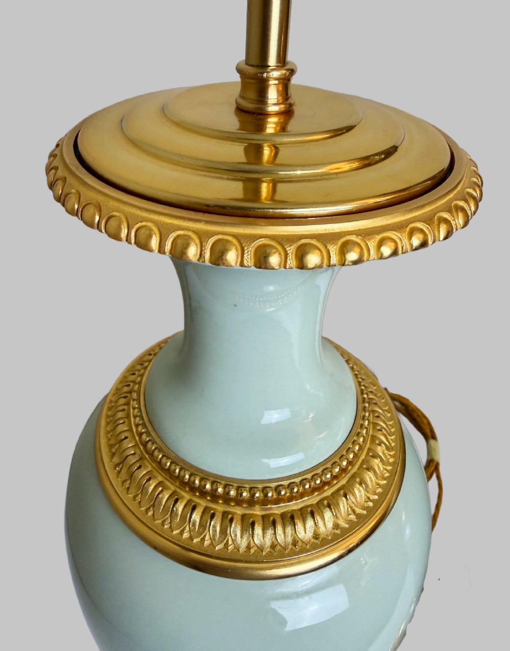 A pair of urn-shaped celadon green porcelain table lamps decorated with white classical figures in low relief, set upon ornate gilded bronze bases. View II