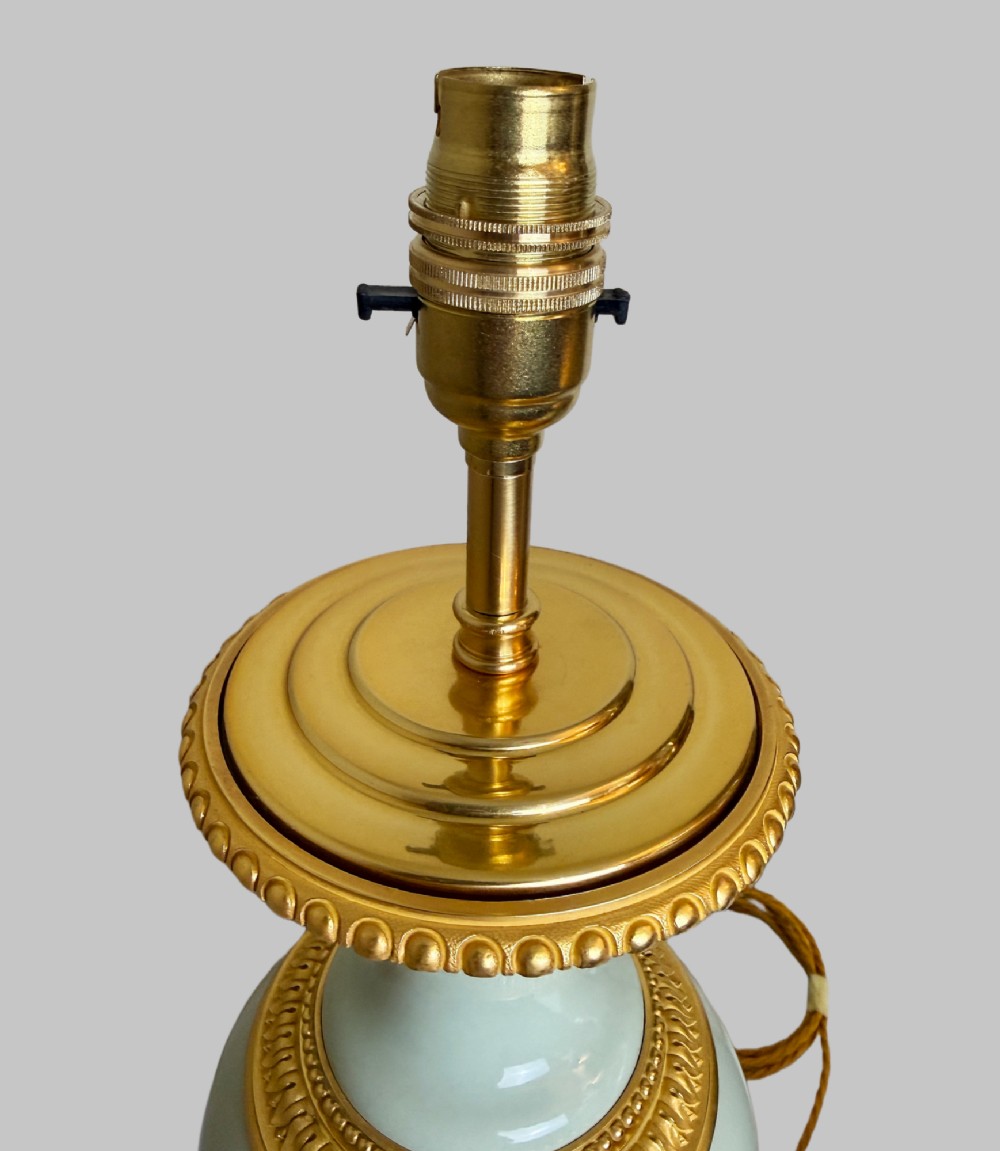 A pair of urn-shaped celadon green porcelain table lamps decorated with white classical figures in low relief, set upon ornate gilded bronze bases. View VII