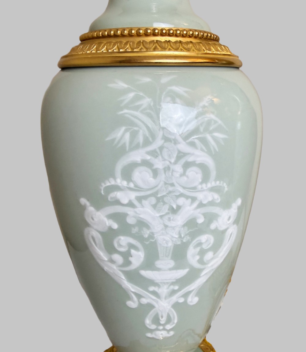 A pair of urn-shaped celadon green porcelain table lamps decorated with white classical figures in low relief, set upon ornate gilded bronze bases. View VIII