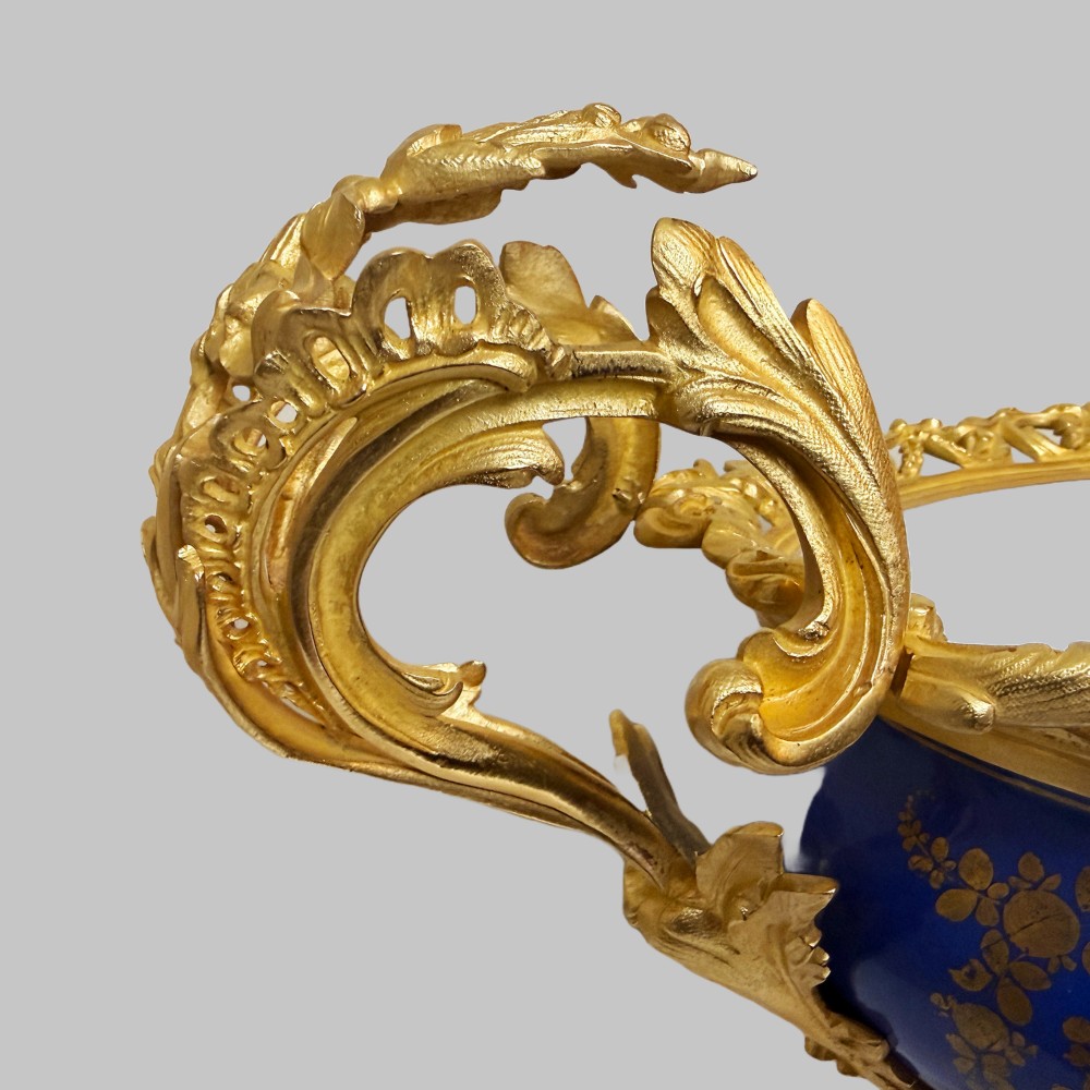 A mid-19th-century cobalt blue porcelain centrepiece bowl featuring a hand-painted pastoral scene, gilded foliage patterns, and cast gilt bronze scroll handles and base. View II