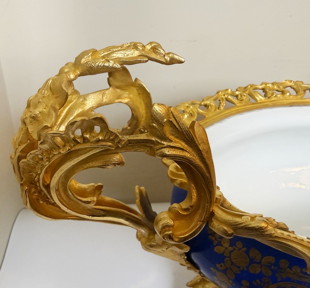 A mid-19th-century cobalt blue porcelain centrepiece bowl featuring a hand-painted pastoral scene, gilded foliage patterns, and cast gilt bronze scroll handles and base. View IV
