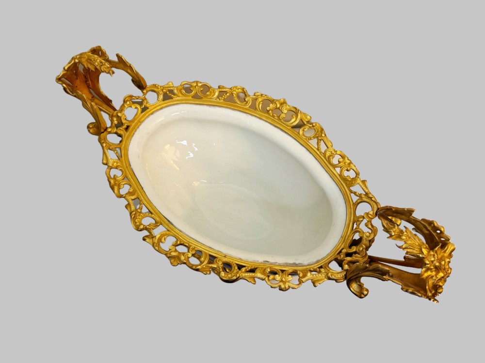 A mid-19th-century cobalt blue porcelain centrepiece bowl featuring a hand-painted pastoral scene, gilded foliage patterns, and cast gilt bronze scroll handles and base. View V
