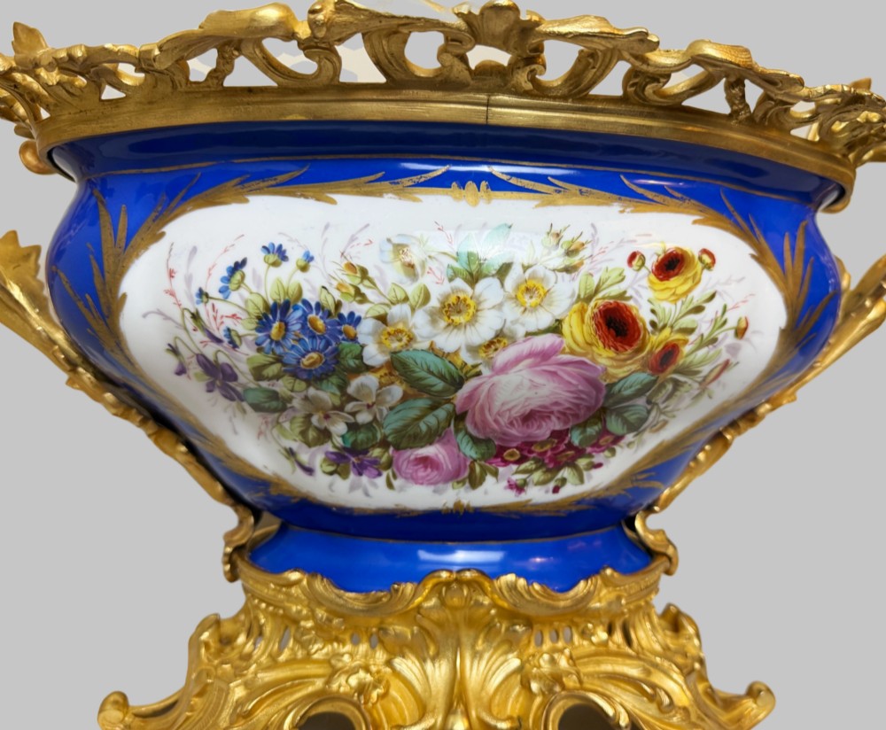 A mid-19th-century cobalt blue porcelain centrepiece bowl featuring a hand-painted pastoral scene, gilded foliage patterns, and cast gilt bronze scroll handles and base. View VI