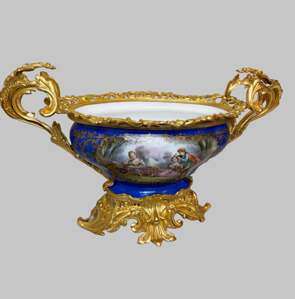 A mid-19th-century cobalt blue porcelain centrepiece bowl featuring a hand-painted pastoral scene, gilded foliage patterns, and cast gilt bronze scroll handles and base. View VIII