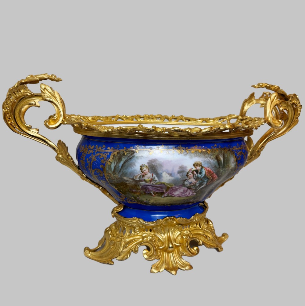 A mid-19th-century cobalt blue porcelain centrepiece bowl featuring a hand-painted pastoral scene, gilded foliage patterns, and cast gilt bronze scroll handles and base. View IX