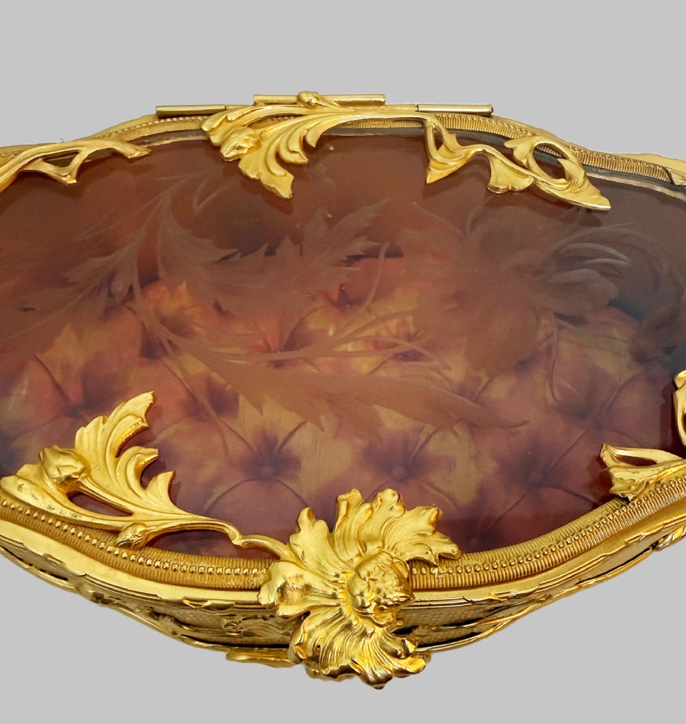 An oval nineteenth-century gilt bronze jewellery box featuring textured foliate relief work, scroll feet, and an etched glass lid. View III
