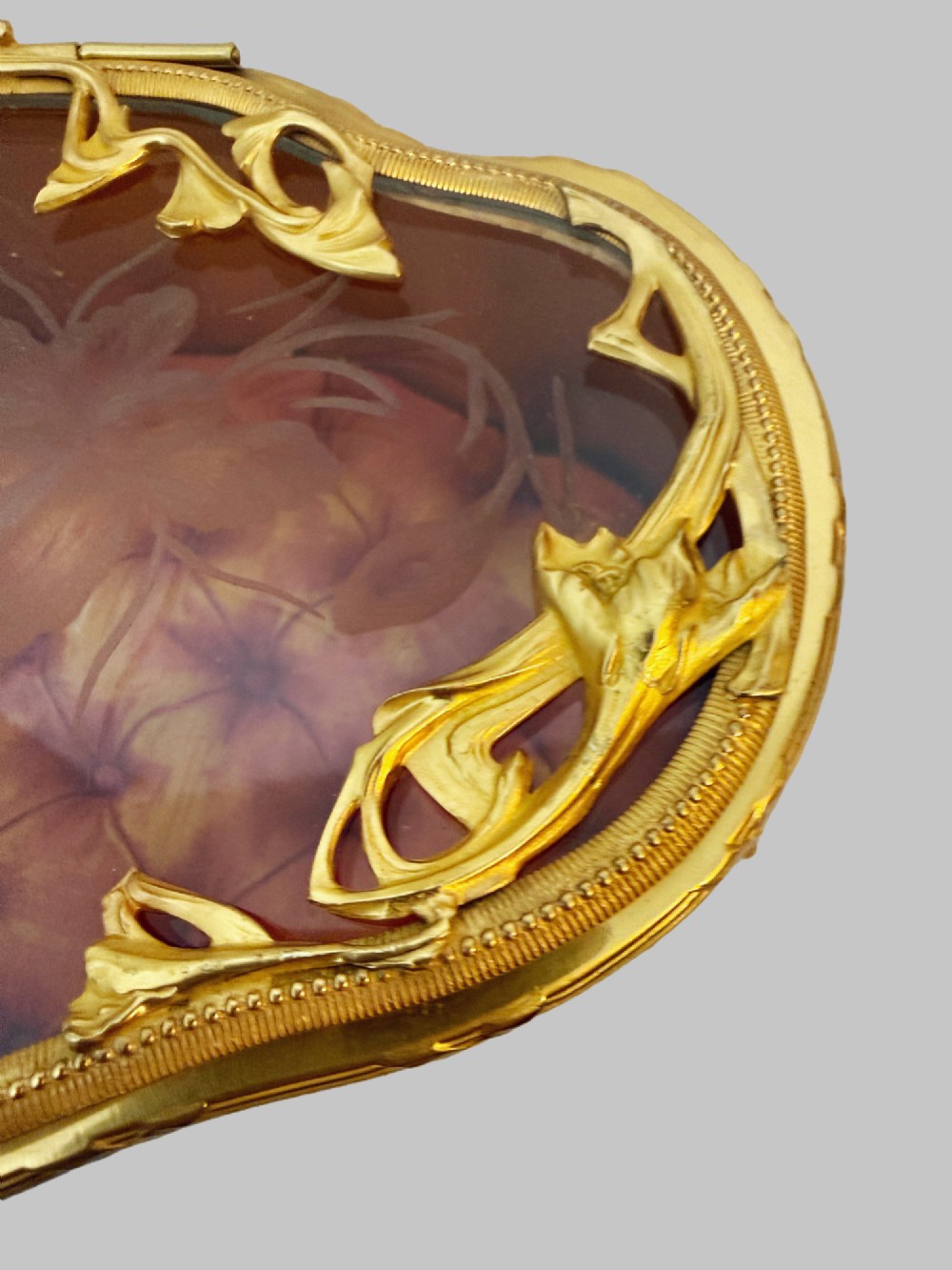 An oval nineteenth-century gilt bronze jewellery box featuring textured foliate relief work, scroll feet, and an etched glass lid. View VI