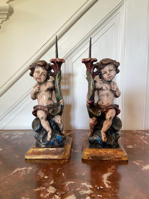 A PAIR OF CONTINENTAL 17TH CENTURY POLYCHROME CANDLESTICKS IN THE FORM OF 2 PUTTO