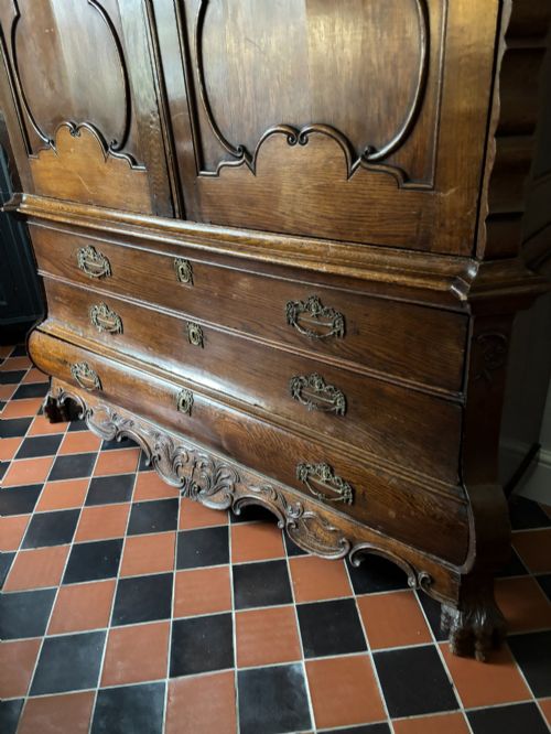 fig 1. An 18th-century Dutch oak linen press featuring an arched pediment, two carved panel doors, three lower drawers, and brass handles.