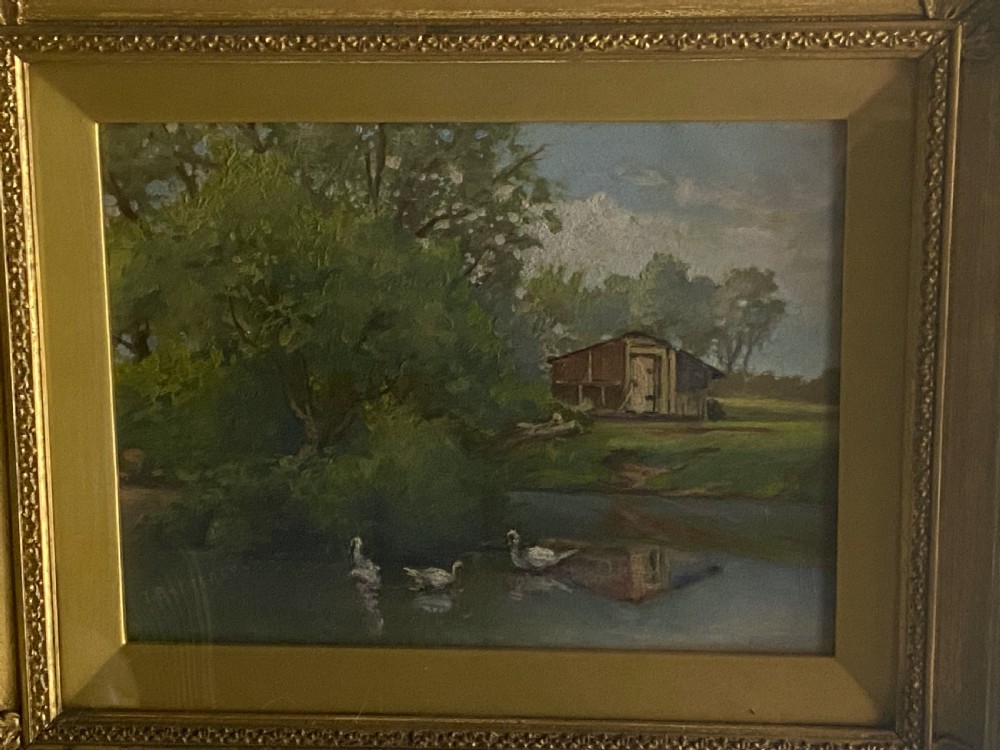 An impressionist oil painting on board depicting a serene rural pond with ducks, surrounding green trees, and a wooden barn, presented in an ornate gilt frame. View IV