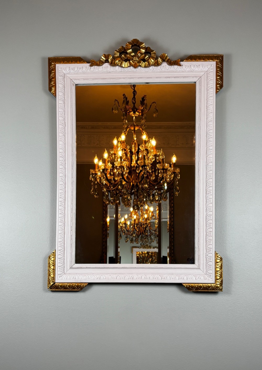 Rectangular late nineteenth-century French mirror featuring a painted white frame with gilded cresting and decorative corner accents.