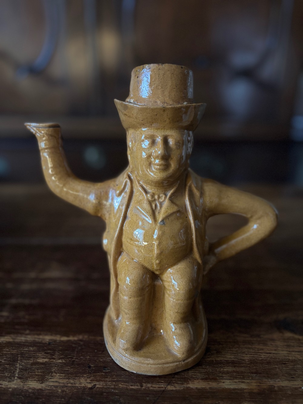 A Victorian treacle-glazed yellowware teapot moulded into the seated figure of John Bull wearing a top hat and waistcoat.