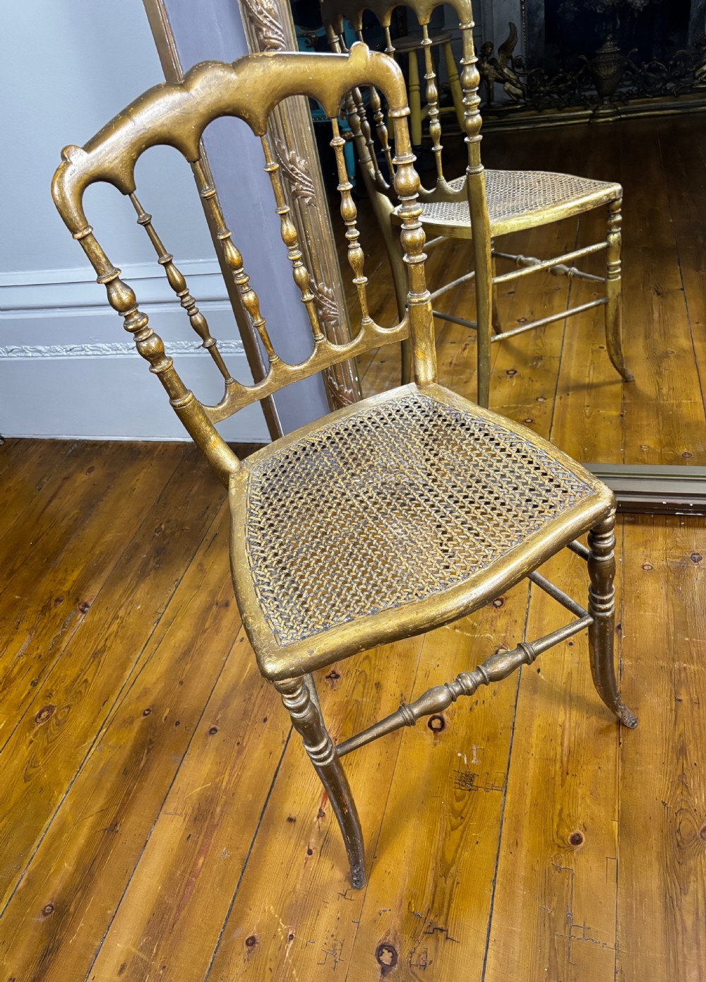 A nineteenth-century French giltwood salon chair with turned back spindles, an arched top rail, woven cane seating, and turned legs. View III