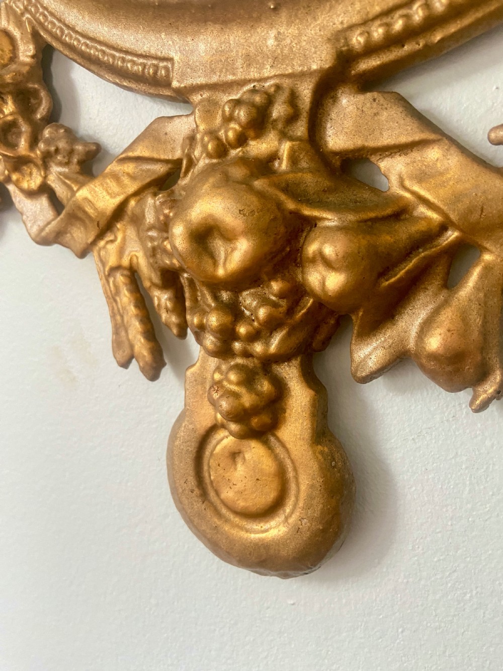 A circular cast iron wall mirror featuring a gold finish, flanked by sculpted cherubs holding a banner inscribed with Welcome Thrice Welcome. View IV