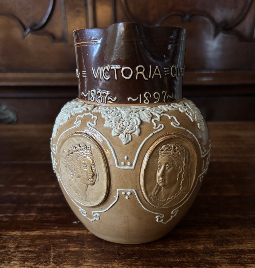 A two-tone brown salt-glazed stoneware jug featuring raised sprigged oval relief medallions of Queen Victoria and white decorative scrollwork, dated 1837-1897.
