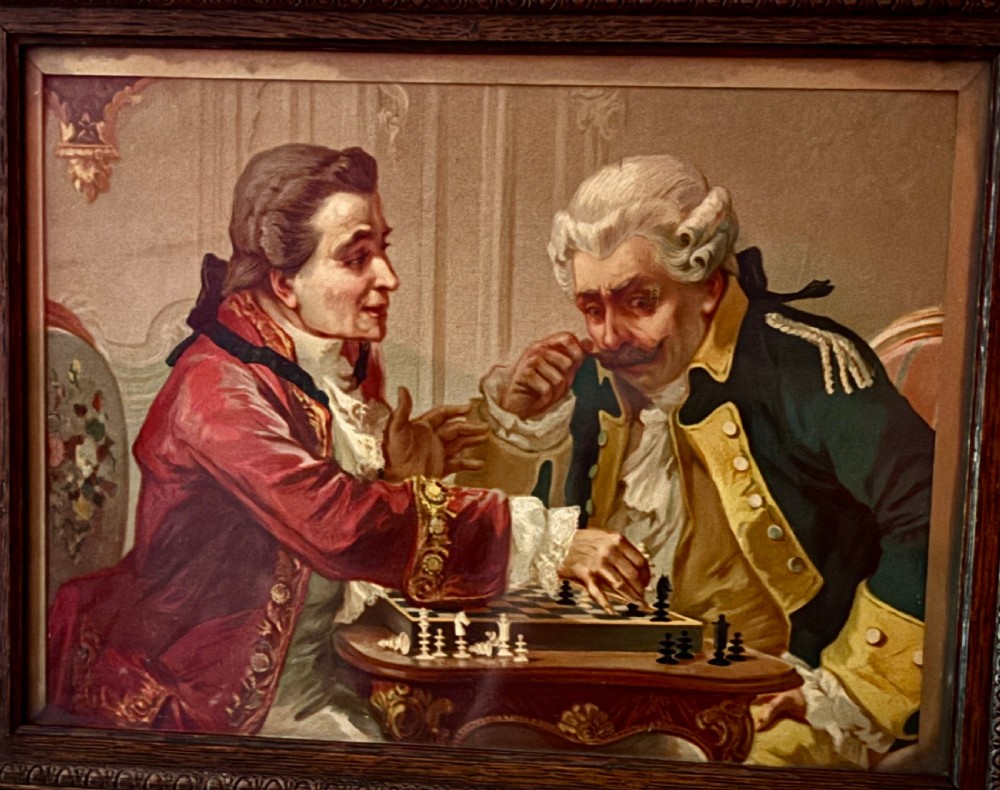 A pair of dark wood framed French oleograph prints depicting 18th-century dressed gentlemen playing cards and chess. View II