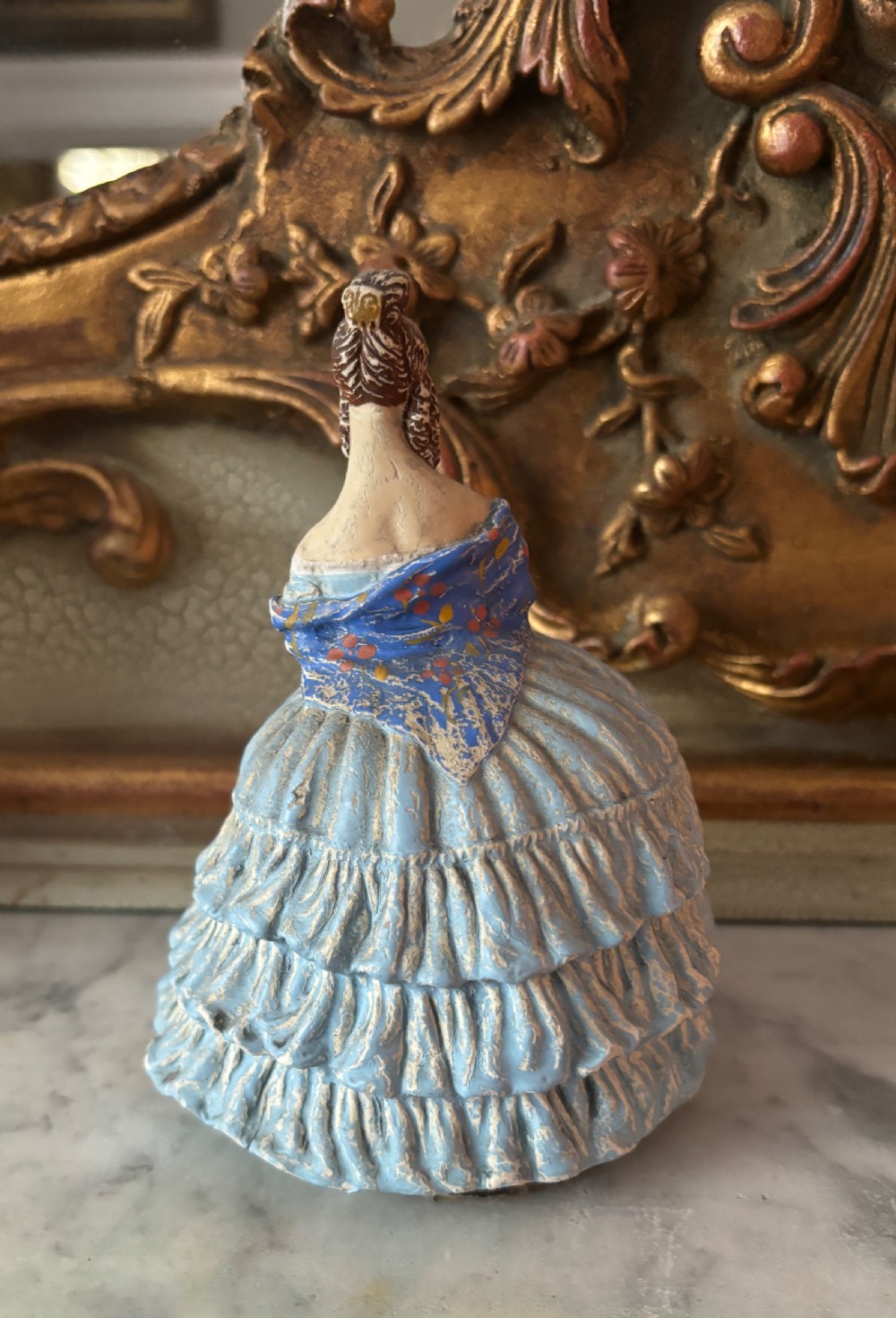 A French papier-mache powder box shaped as a lady in a light blue tiered dress holding a small bouquet of flowers. View III