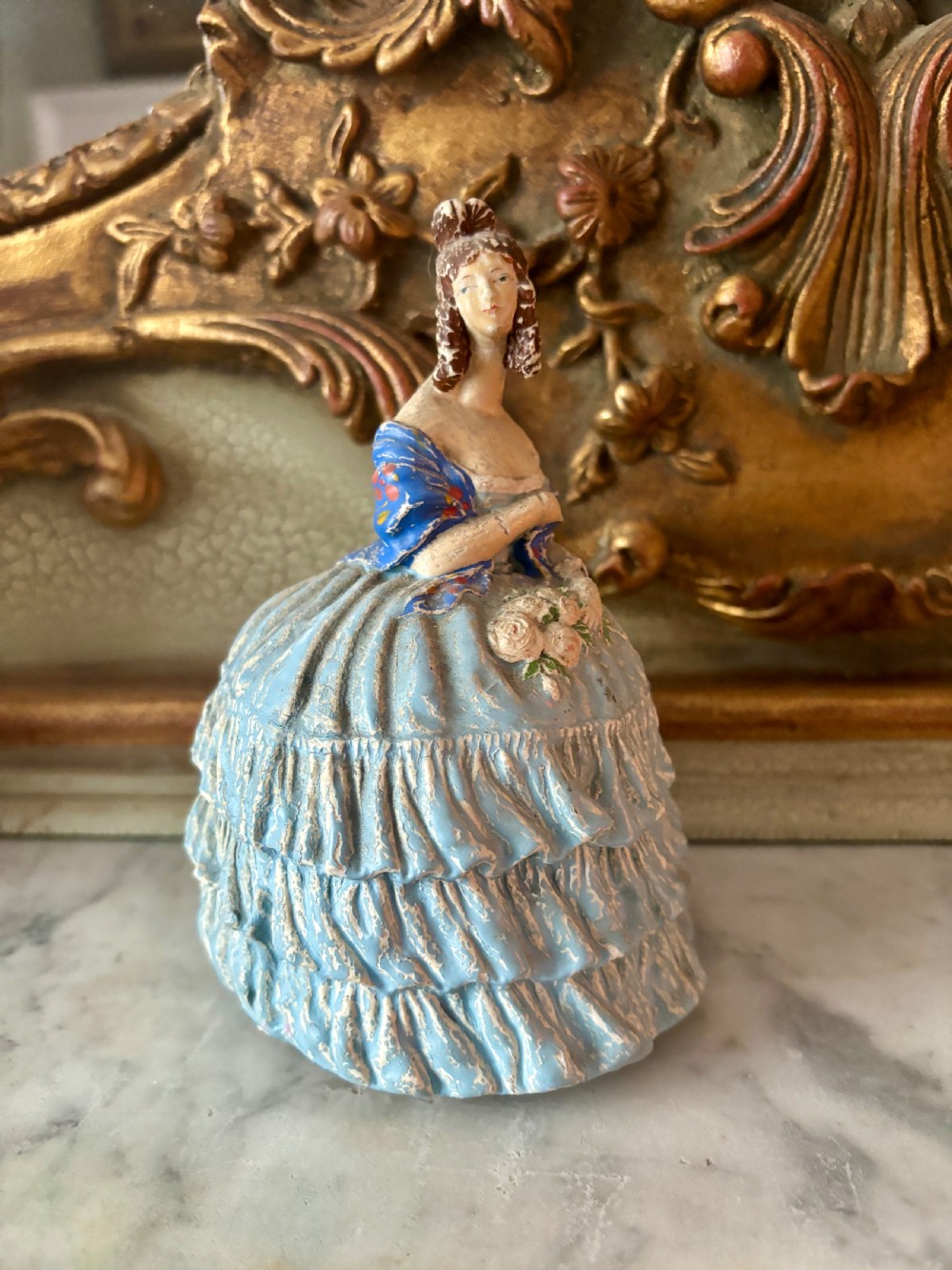 A French papier-mache powder box shaped as a lady in a light blue tiered dress holding a small bouquet of flowers. View IV