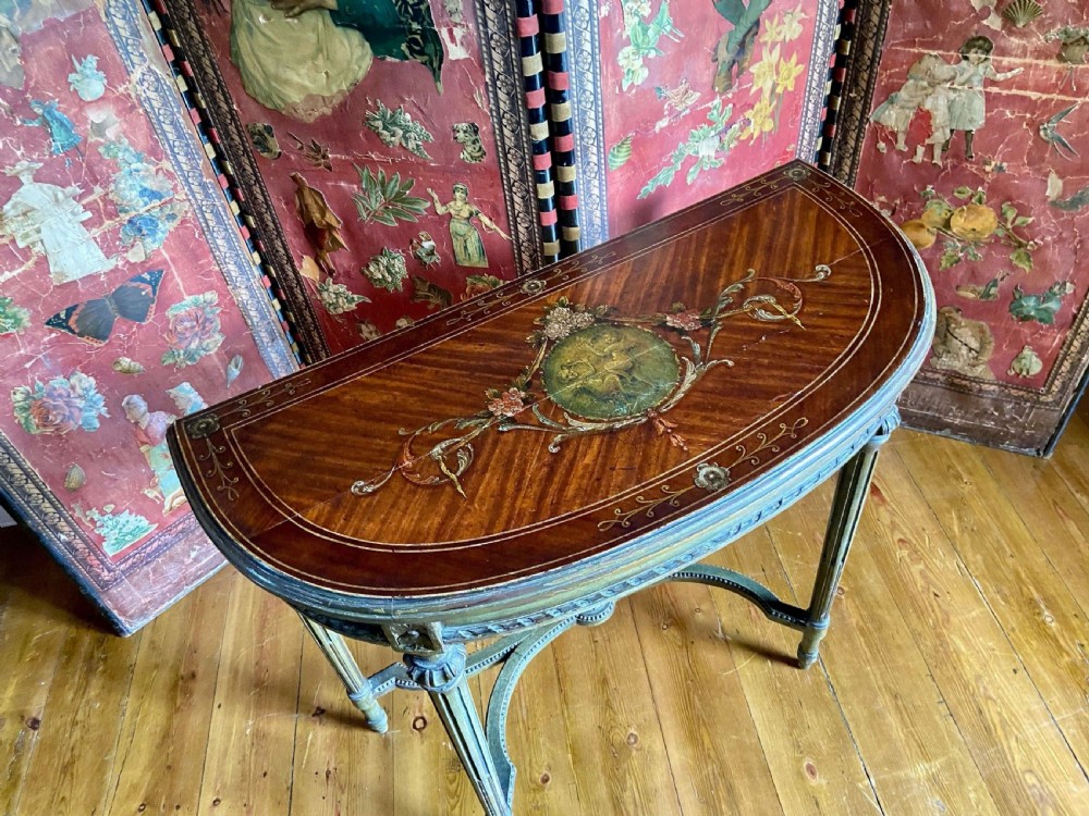 A French demi-lune console table showcasing a semicircular satinwood top decorated with hand-painted floral swags and a central cherub medallion. View V