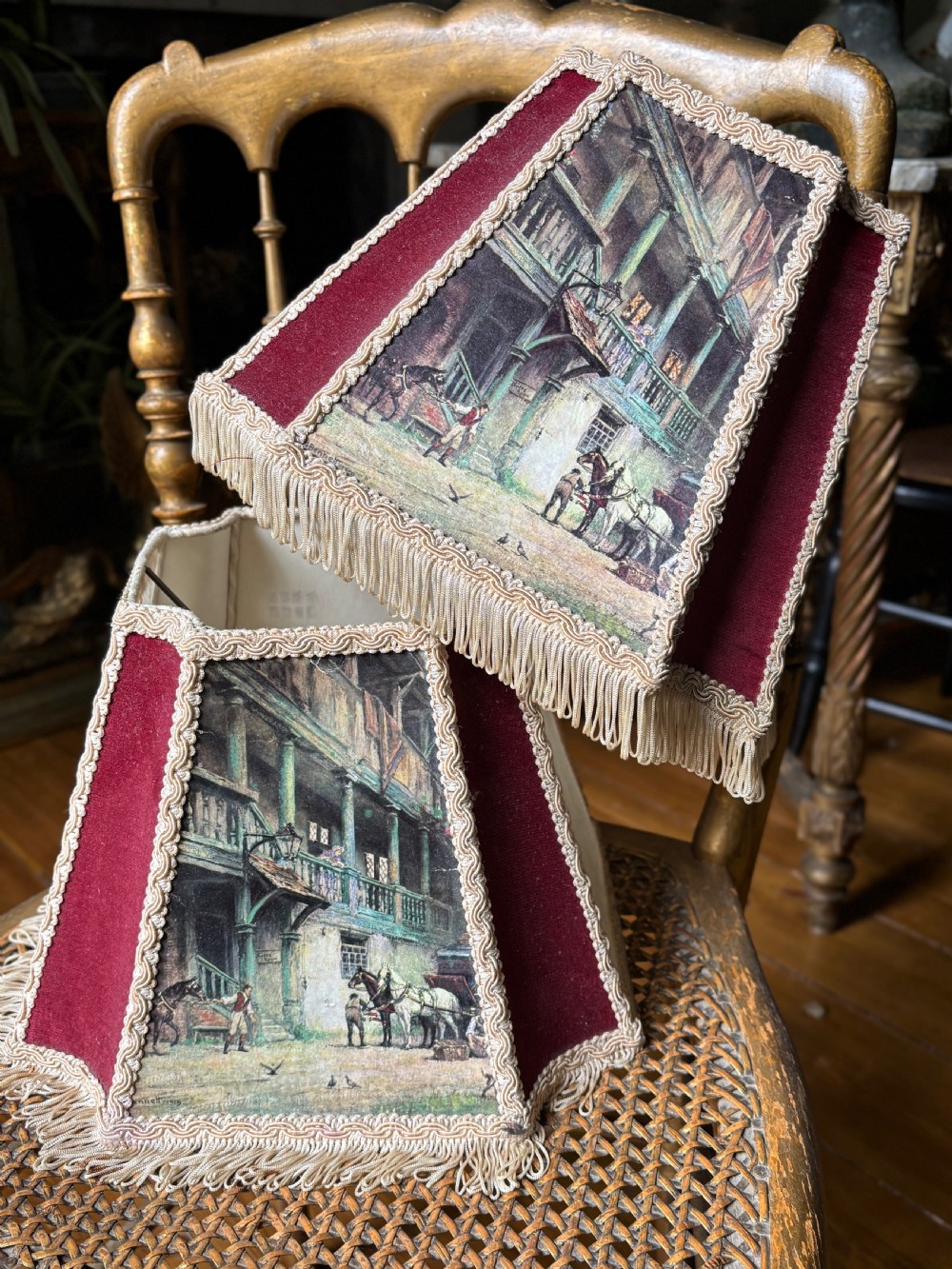 A pair of 1930s hexagonal lampshades featuring printed tavern scenes, deep burgundy fabric panels, braid trim, and lower fringe. View II