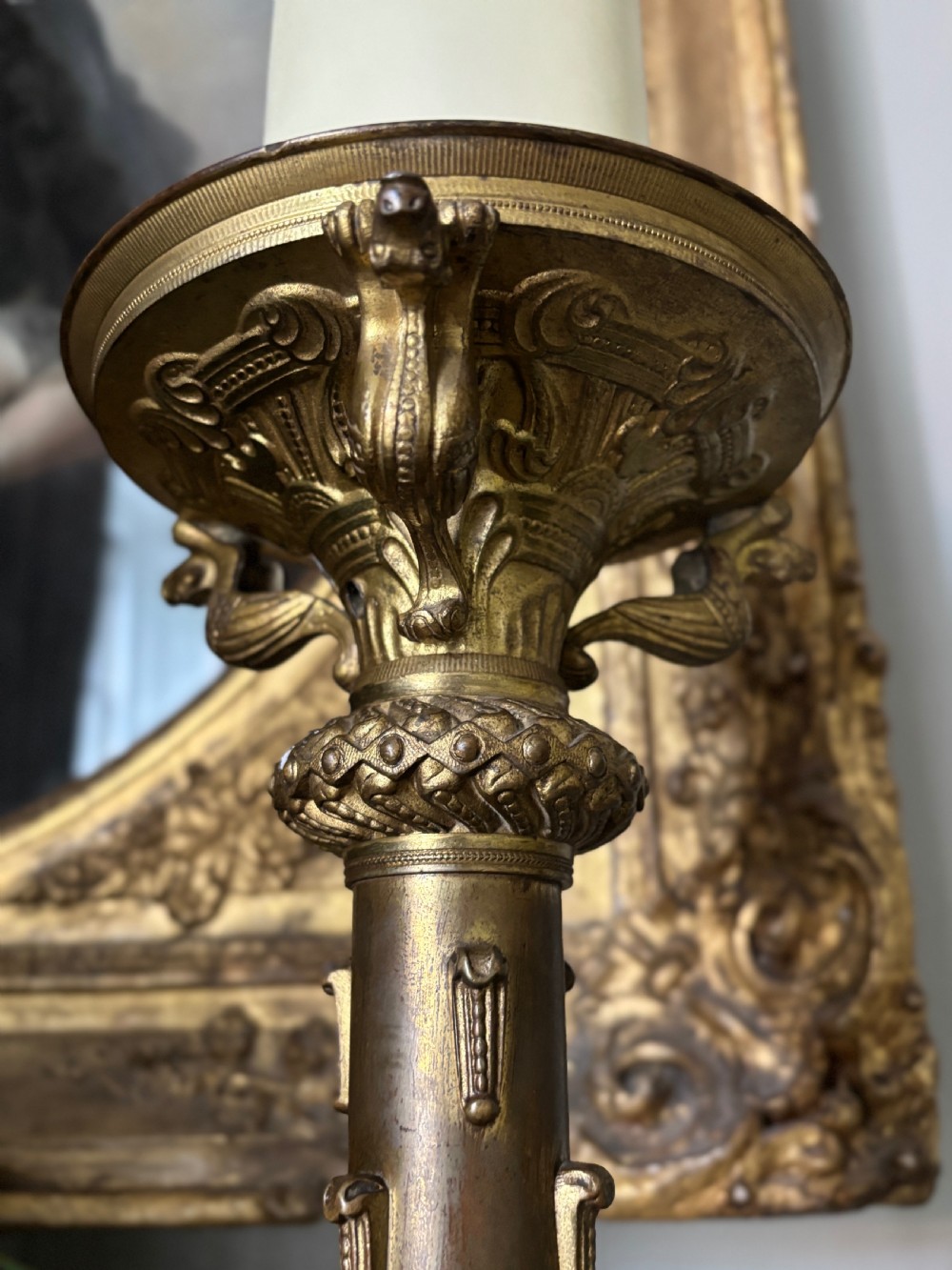 A pair of large French 19th-century gilt bronze candlesticks featuring ornate tripod bases, detailed knapped columns, and wide drip pans. View V