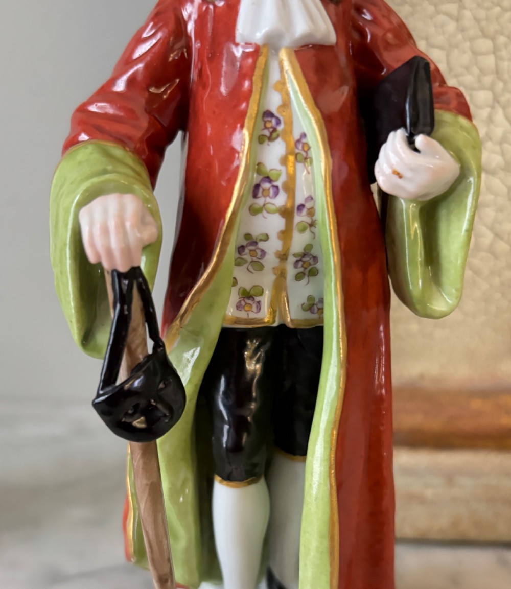 A pair of hand-painted French porcelain figurines depicting an 18th-century man and woman in period costume standing on gilded scroll bases. View VII