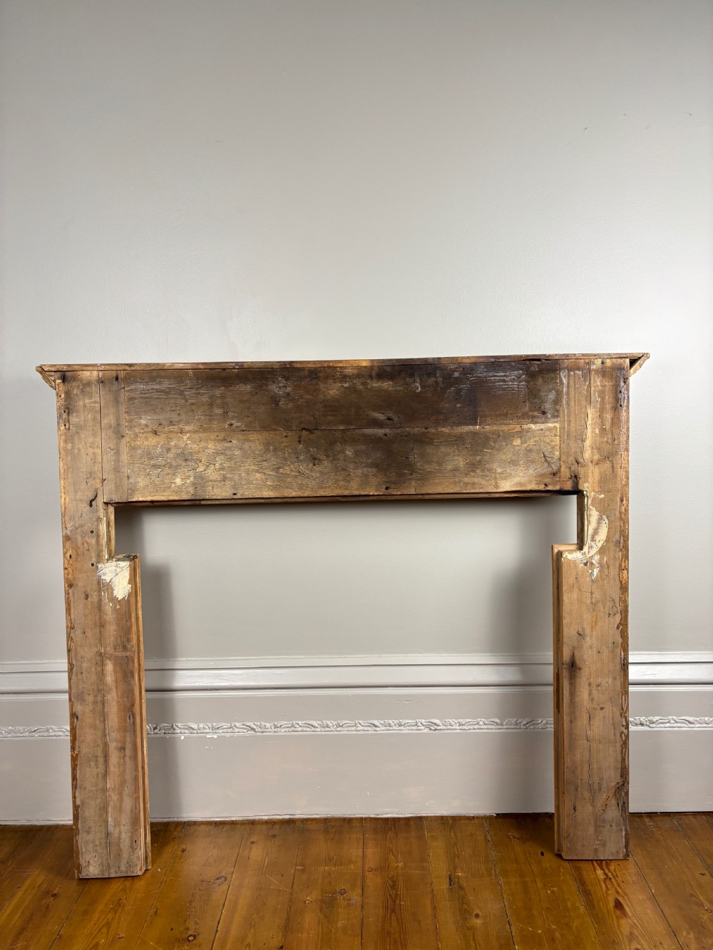 A carved Georgian pine fire surround featuring egg-and-dart moulding, floral swags, and ribbon motifs in a natural timber finish. View X