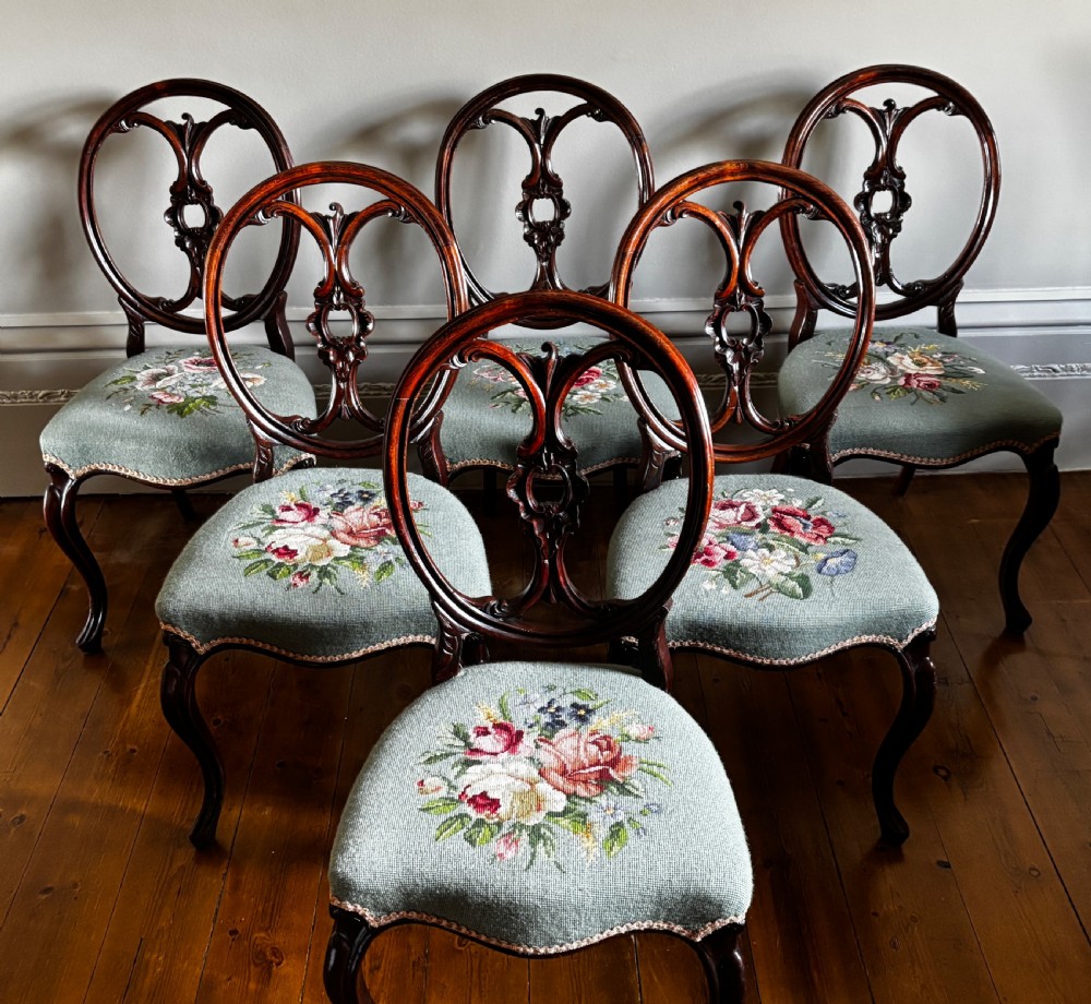 A set of six Victorian rosewood dining chairs with carved balloon backs and duck egg blue needlepoint floral seats.