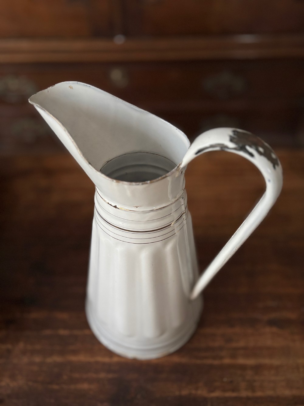 A tall white French enamelware water jug featuring a fluted lower body, thin gold gilt line details, an arched handle, and a raised spout. View IV