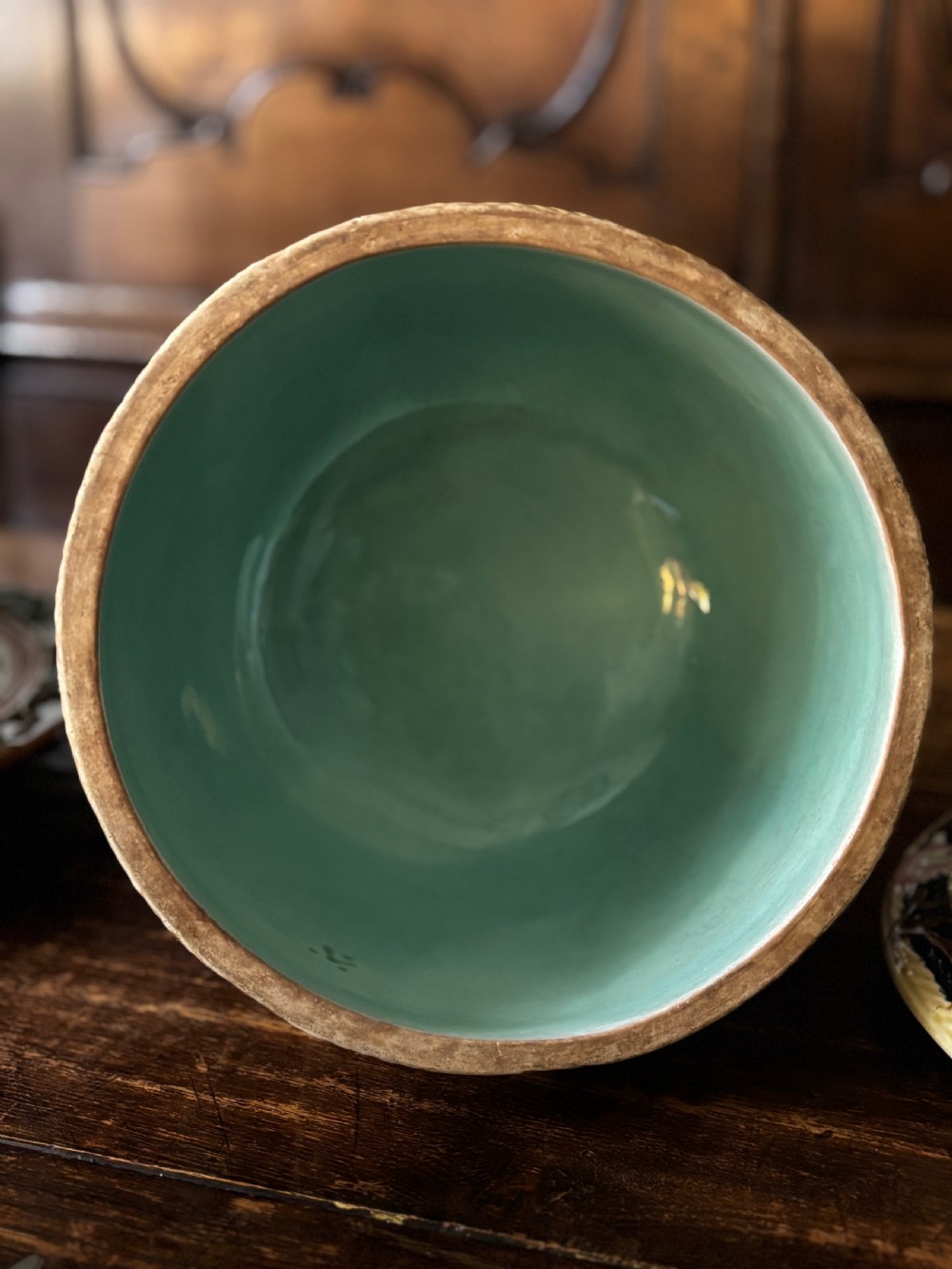 A Victorian majolica cheese dome featuring a cobalt blue glazed body, relief-moulded green leaves, cream rope arches, and pink bows, set on a matching round base. View IV