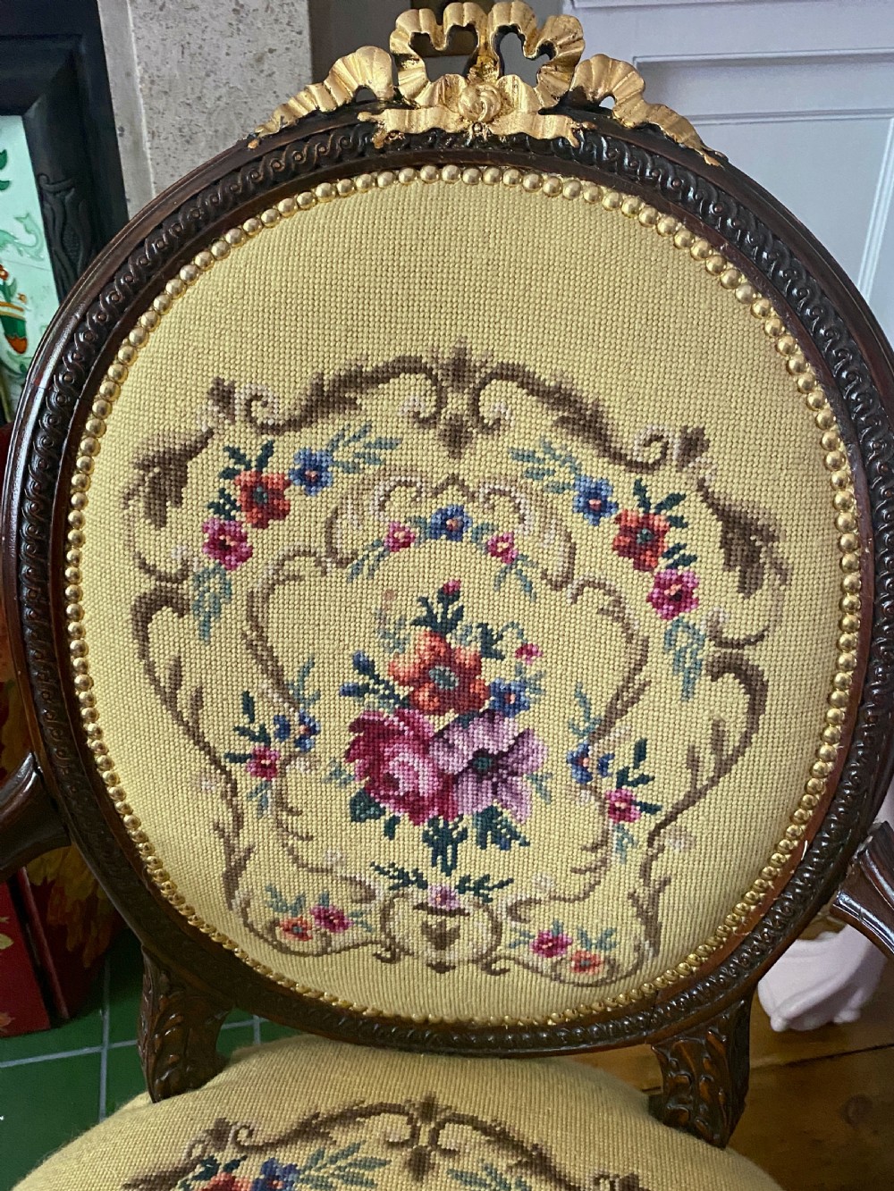 A French Louis XVI style open armchair featuring a dark carved wood frame, fluted legs, and yellow needlepoint upholstery decorated with floral motifs. View IV