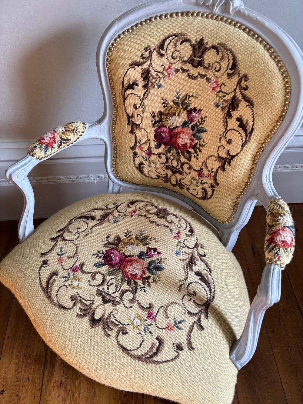 A French Rococo Revival open armchair featuring a grey painted carved frame with yellow floral needlepoint upholstery. View II