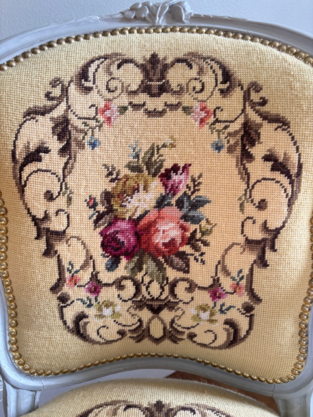 A French Rococo Revival open armchair featuring a grey painted carved frame with yellow floral needlepoint upholstery. View III