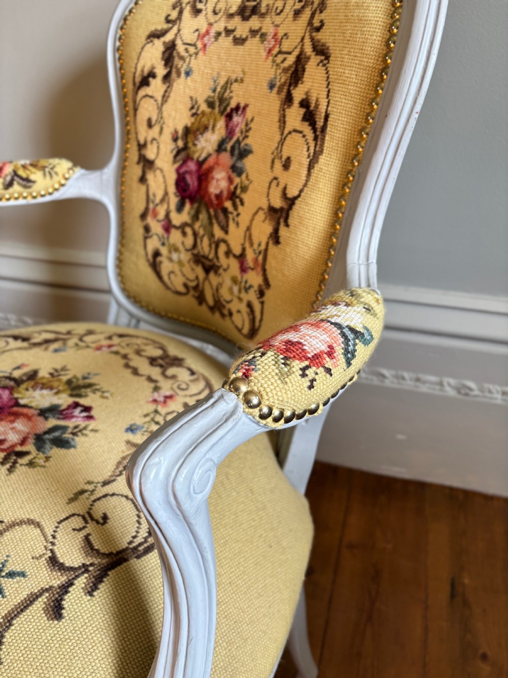 A French Rococo Revival open armchair featuring a grey painted carved frame with yellow floral needlepoint upholstery. View IV