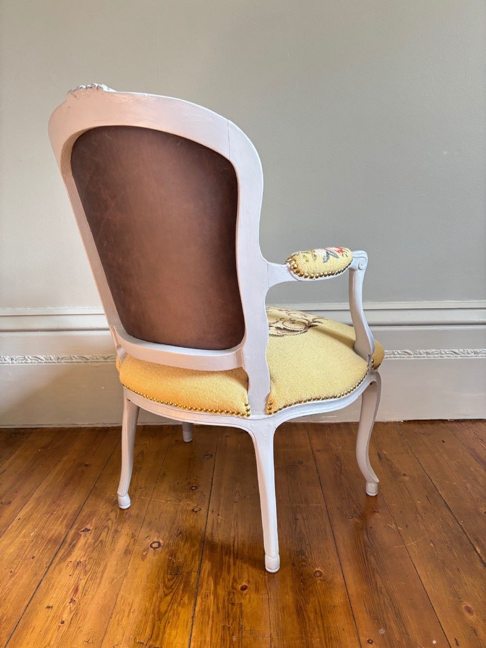 A French Rococo Revival open armchair featuring a grey painted carved frame with yellow floral needlepoint upholstery. View VII