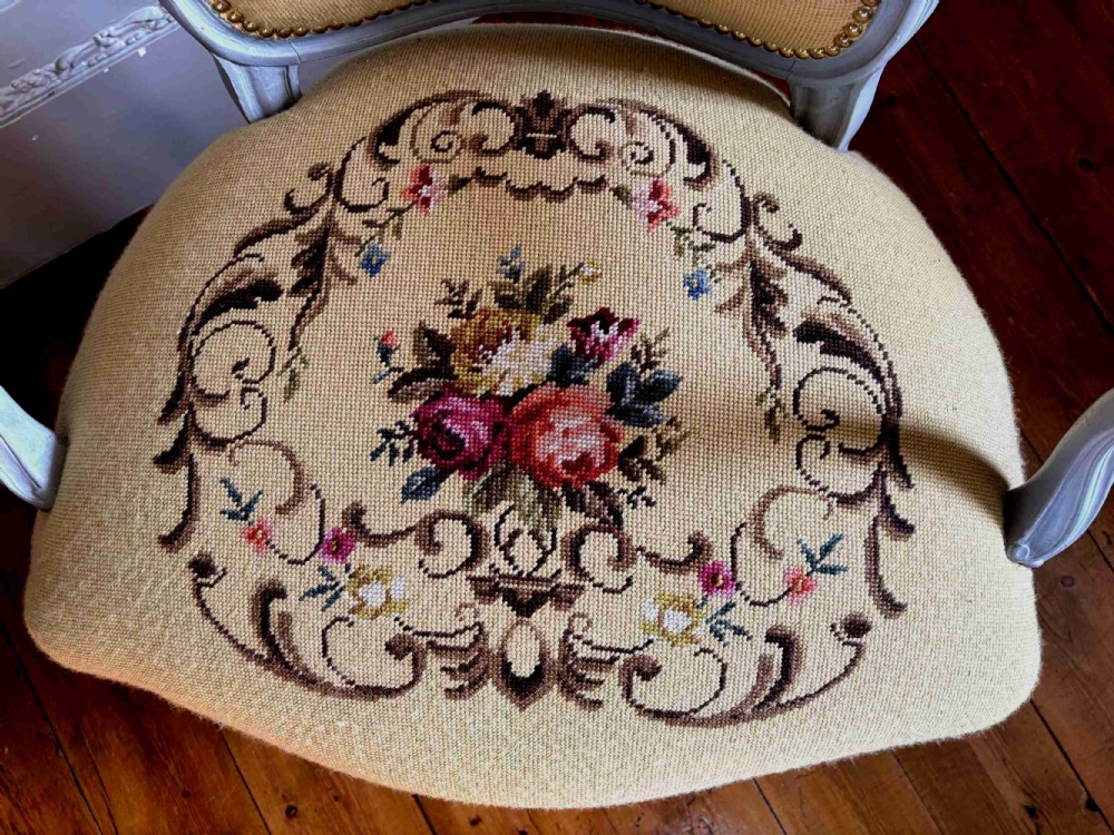 A French Rococo Revival open armchair featuring a grey painted carved frame with yellow floral needlepoint upholstery. View V