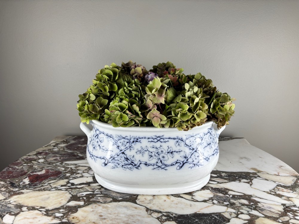A large oval Victorian blue and white transferware ceramic footbath featuring two side handles and a floral branch pattern.