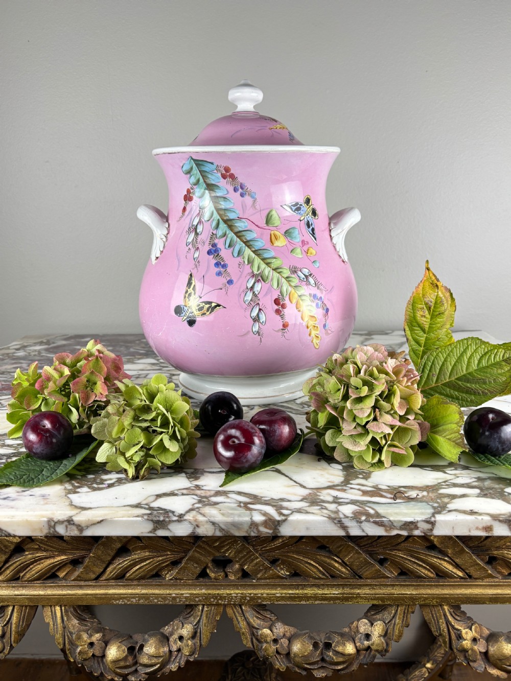 A Victorian Minton ceramic lidded pail featuring hand-painted butterflies and botanical foliage over a pink ground with twin white handles. View II