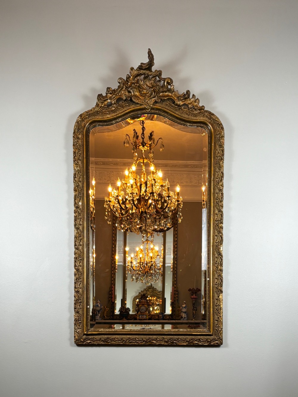 An antique rectangular French Louis Philippe giltwood wall mirror featuring rounded upper corners, an ornate carved crest, and a gold leaf frame. View III
