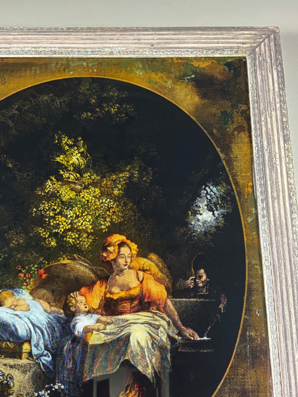 A Georgian reverse print on glass displaying a figure scene inside an oval vignette within a silvered moulded frame. View V