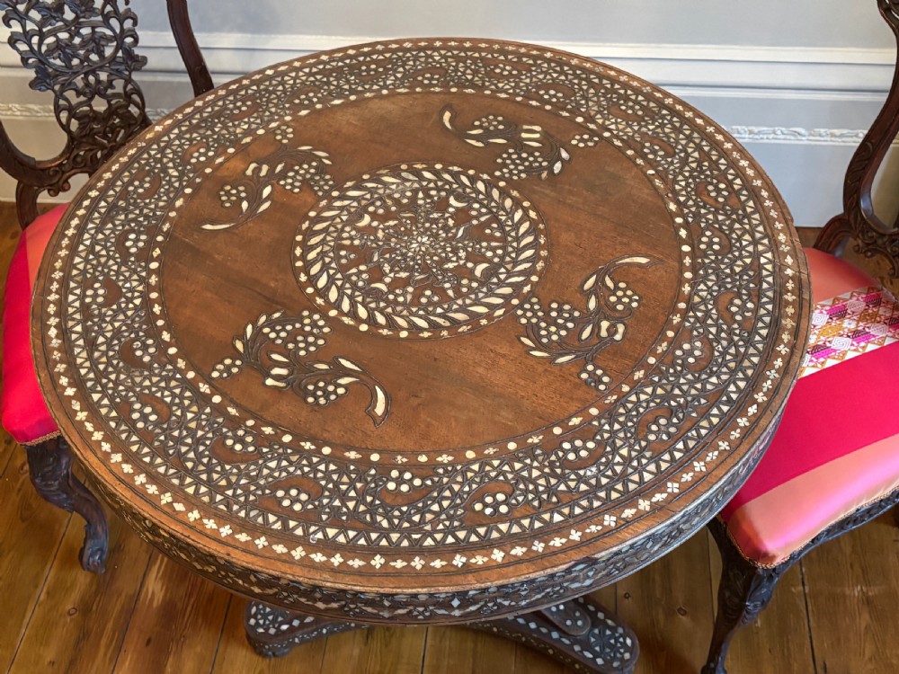 A 19th-century round Anglo-Indian pedestal table featuring mother-of-pearl inlay across the circular top, apron, turned column, and tripod base. View IV