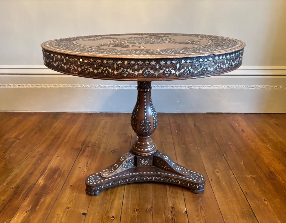 A 19th-century round Anglo-Indian pedestal table featuring mother-of-pearl inlay across the circular top, apron, turned column, and tripod base. View IX