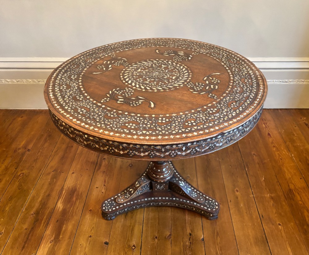 A 19th-century round Anglo-Indian pedestal table featuring mother-of-pearl inlay across the circular top, apron, turned column, and tripod base. View X