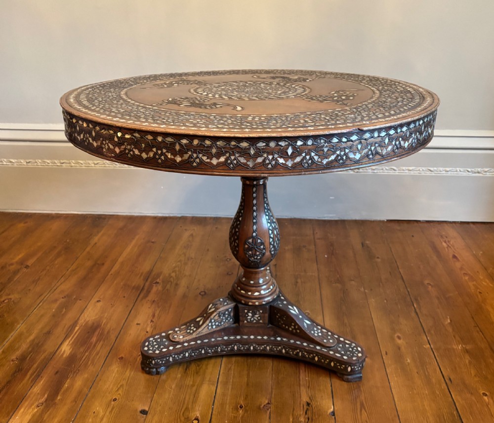 A 19th-century round Anglo-Indian pedestal table featuring mother-of-pearl inlay across the circular top, apron, turned column, and tripod base.
