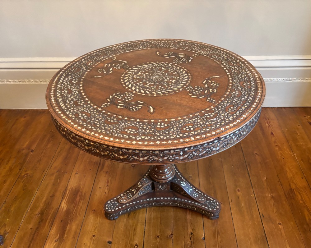 A 19th-century round Anglo-Indian pedestal table featuring mother-of-pearl inlay across the circular top, apron, turned column, and tripod base. View XIII